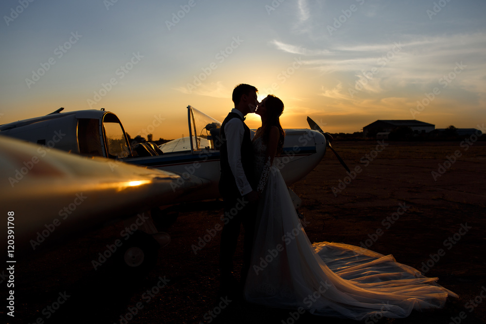 Silhouette of bride and groom near the airplane. Honeymoon concept