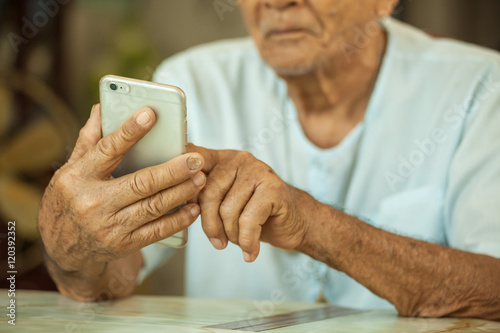 Happy asian senior man using the mobile phone at home