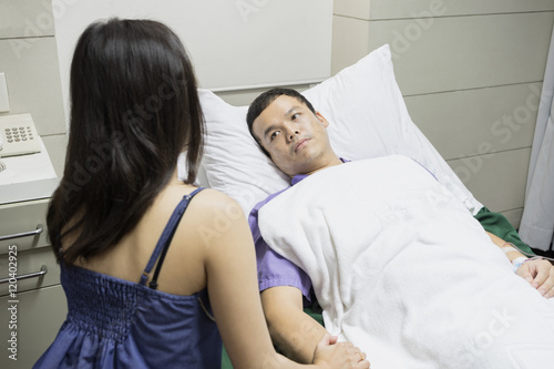 man a husband on bed as patient in hospital or clinic with woman a wife take care on hospital bed side with love and care