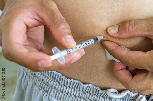 Diabetes patient gets an insulin injection in abdomen area,selective focus.