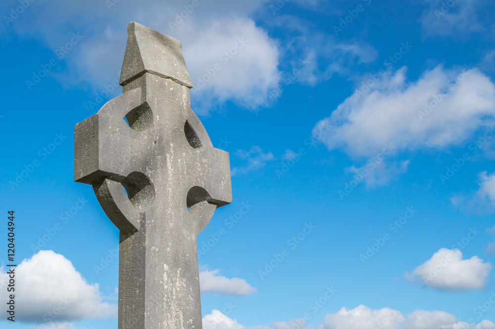 Old stone celtic cross on a bright sunny day with cloudy sky. Old stone celtic cross on a bright sunny day with cloudy sky.