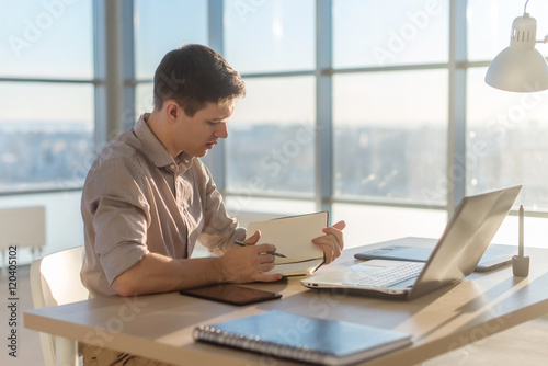 Man freelancer writing on notebook at home or office.