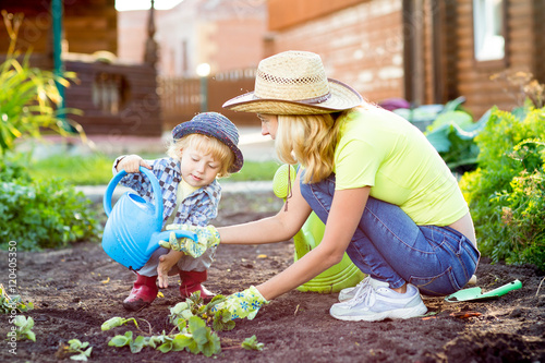 Child boy helps to mother working in the garden