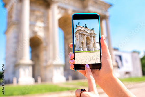 Holding phone with photo of triumphal arch in Milan city.