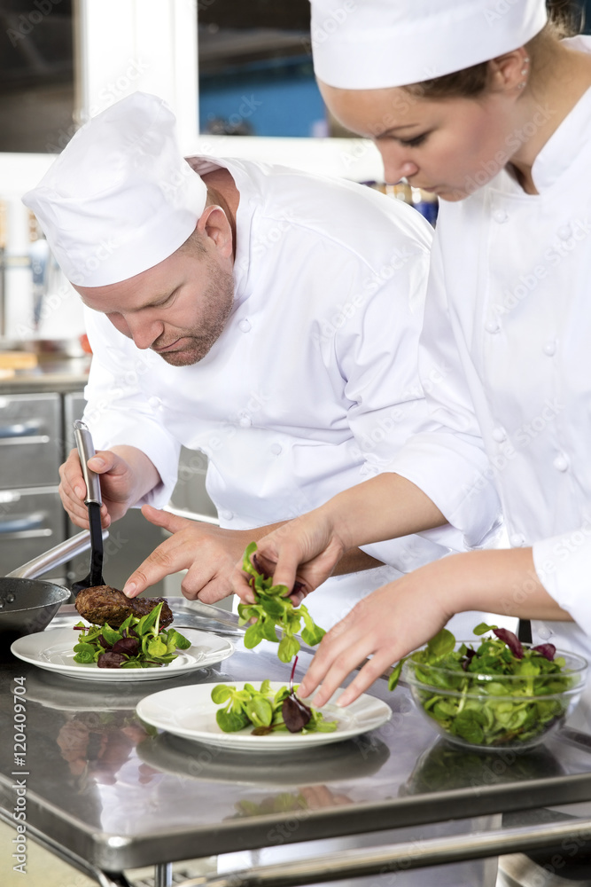 Two dedicated chefs prepares steak dish at gourmet restaurant