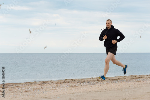 Молодой мужчина бегает по берегу моря photo