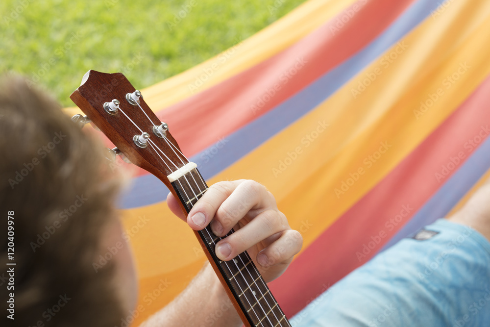 Fototapeta premium Detail of man relaxing on a hammock and playing ukulele