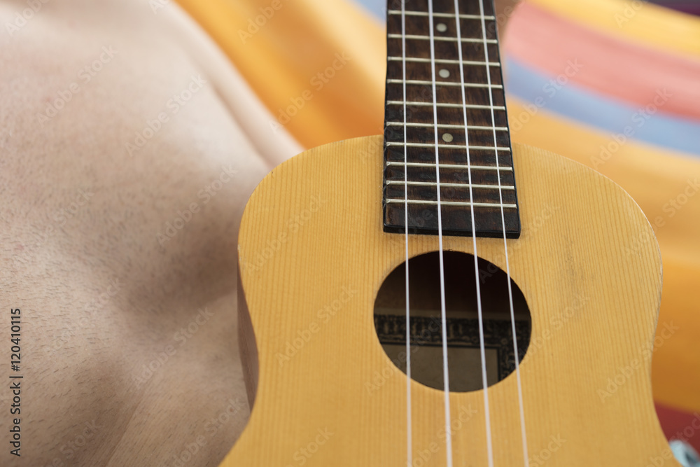 Obraz premium Detail of man relaxing on a hammock and playing ukulele