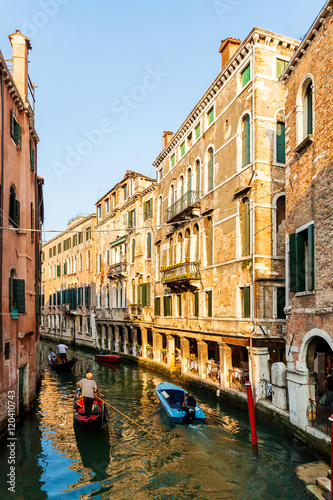 View from the bridge on the small canals in Venice. Beautiful scenic street with water and boats. Bright colorful houses on the water. Italy.