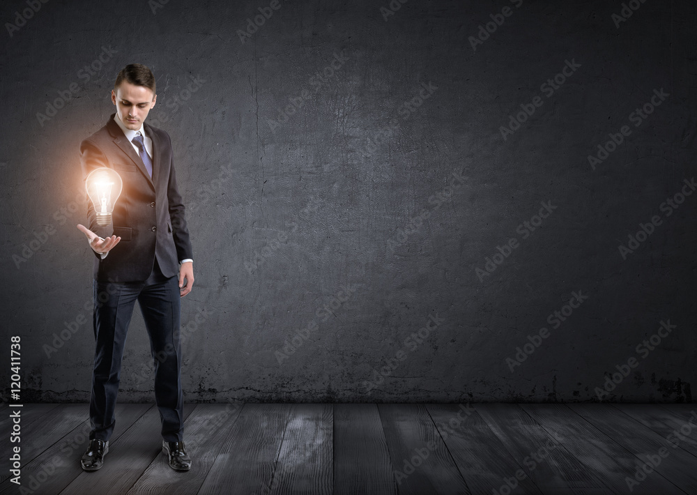 Front view of businessman standing and holding glowing light bulb in his hand Front view of businessman standing and holding glowing light bulb in his hand