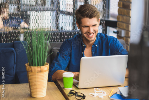 Bilde på lerret young freelancer in front of a laptop smiling with teeth