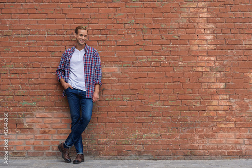 Cuadro en lienzo Handsome guy standing near brick wall