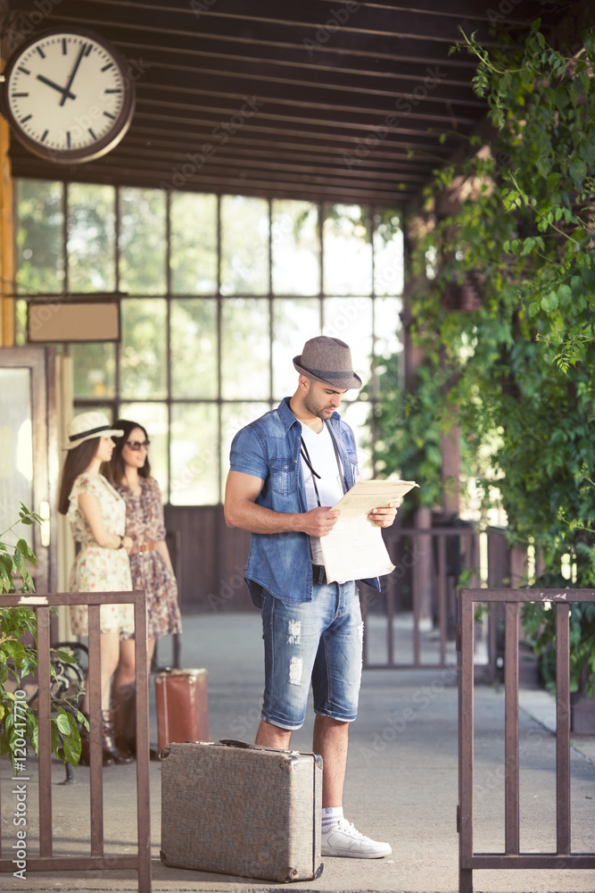 Handsome young man reading a newspapers at the trainstation. Handsome young man reading a newspapers at the trainstation.