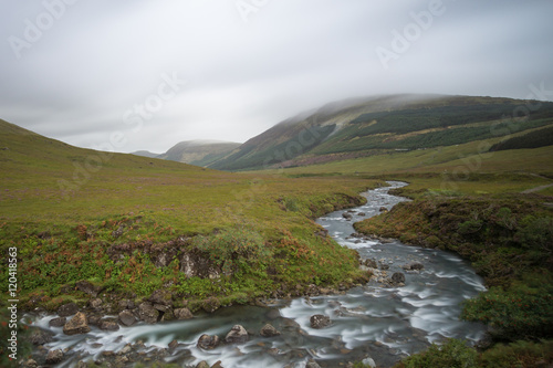 River flows through a valley. Hilltop in clouds