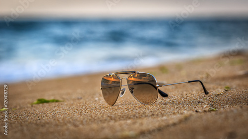 Sunglasses on the beach with sunrise reflections