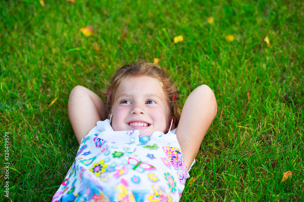little girl smiling and resting on the grass a summer day little girl smiling and resting on the grass a summer day