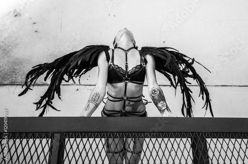 Bovenaanzicht zwart-wit foto van mooie verleidelijke engel vrouw draagt lingerie en leren riemen op het dak over witte muur