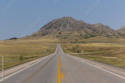 Bild auf Leinwand Bear Butte Highway / A highway leading to a butte.