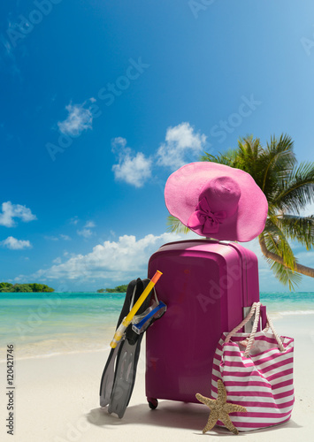 Fototapeta Naklejka Na Ścianę i Meble -  Suitcase and big straw hat on the beach