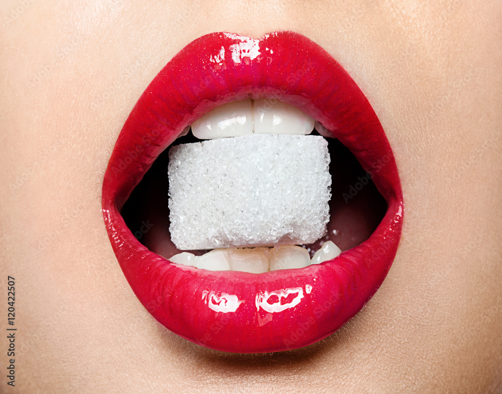 Fototapeta premium Beautiful red female lips with a piece of sugar in his mouth