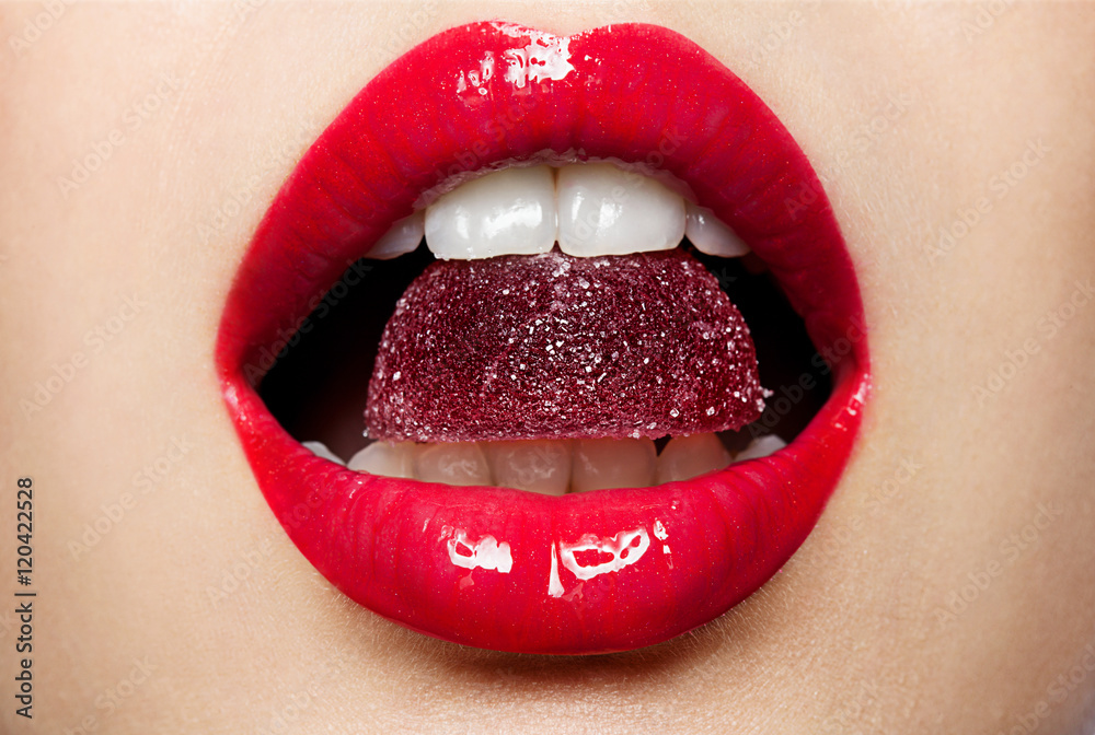 Fototapeta premium Beautiful red lips with a piece of fruit jelly
