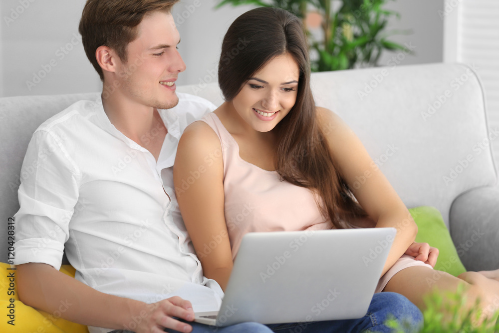 Beautiful couple surfing internet on laptop at home Beautiful couple surfing internet on laptop at home