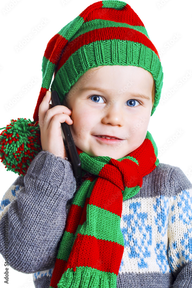 Fotografie Christmas boy in knitted cloths makes a phone call to Santa