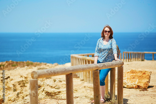 Woman at wooden walkway along the coastline in Algarve region