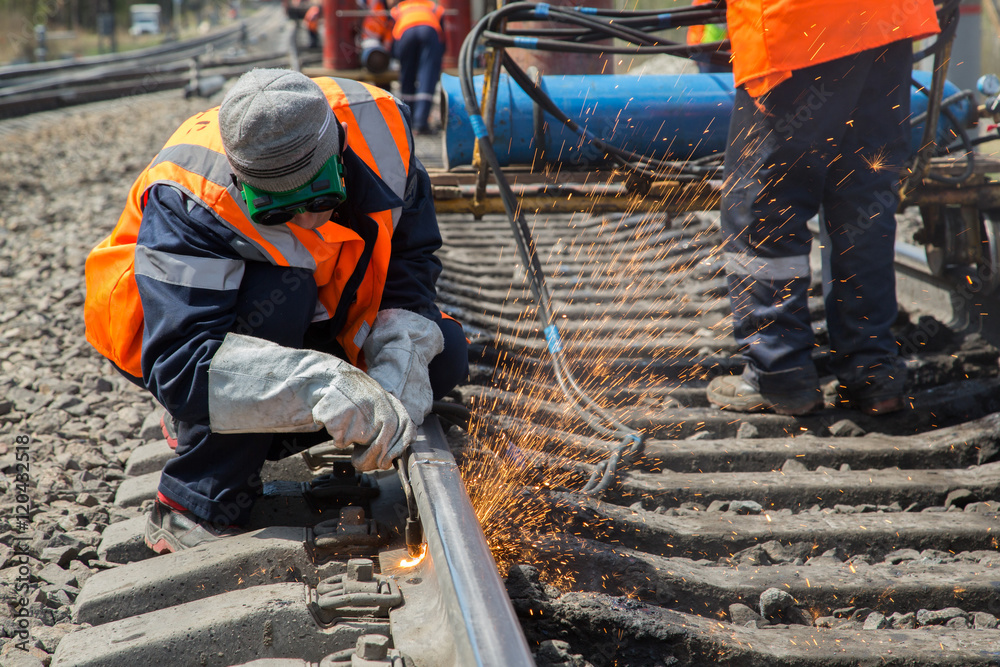 Naklejka premium photo of worker doing gas cutting on rails