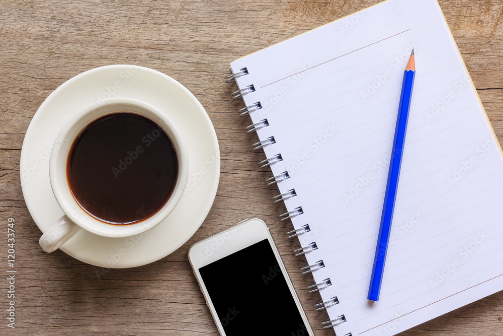 Top view and close up of old wooden desktop with notebook, smartphone, coffee cup and pencil. Top view and close up of old wooden desktop with notebook, smartphone, coffee cup and pencil.