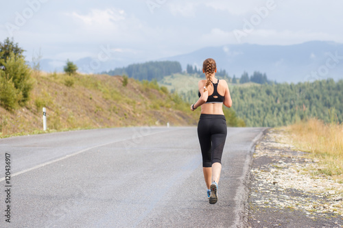 Young slim woman running on mountain road © skumer