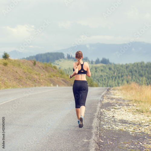 Young slim woman running on mountain road