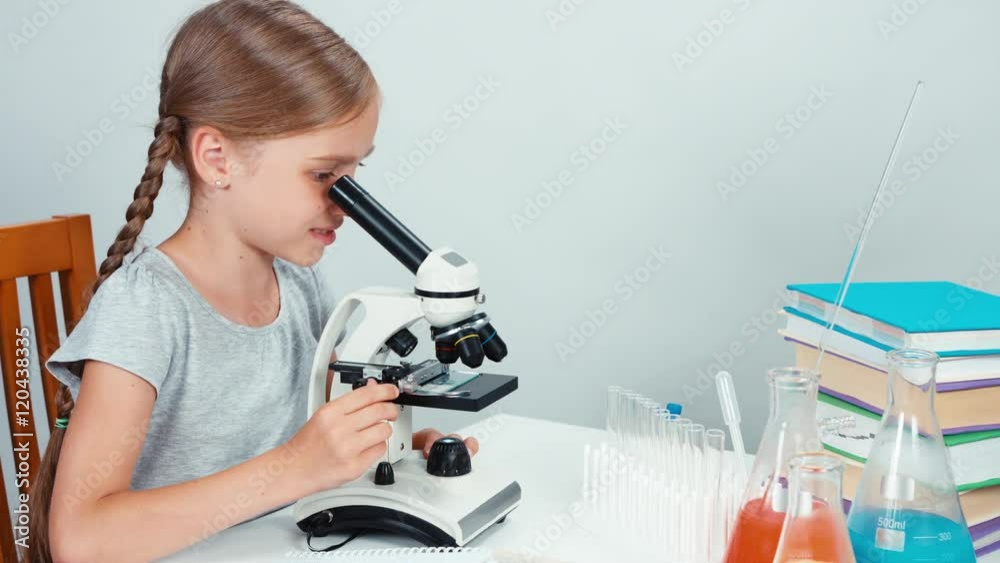 Close up portrait schoolgirl child 7-8 years using microscope and looking with smile at camera. Thumb up. Panning Close up portrait schoolgirl child 7-8 years using microscope and looking with smile at camera. Thumb up. Panning