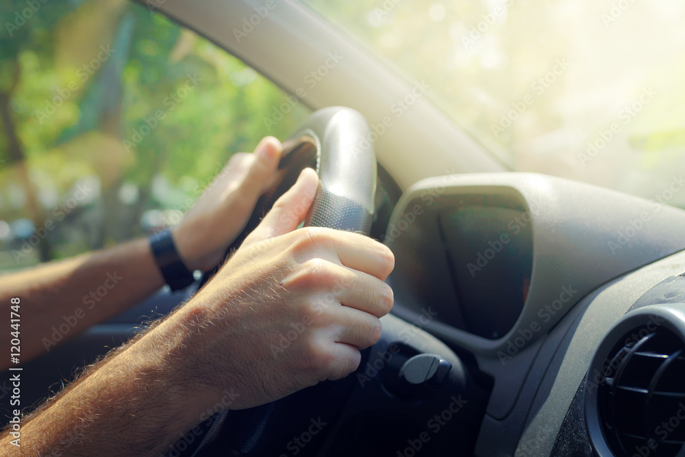 Male hands holding car steering wheel