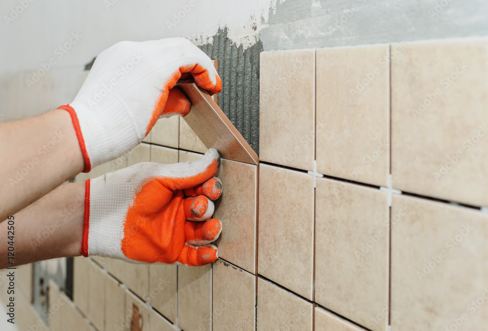 Worker  putting  tiles on the wall in the kitchen. - obrazy, fototapety, plakaty 