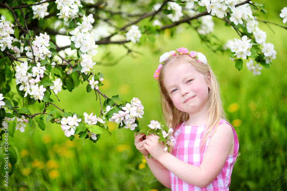 Adorable little girl in blooming apple tree garden on spring day Adorable little girl in blooming apple tree garden on spring day