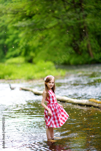 Fototapeta Naklejka Na Ścianę i Meble -  Cute little girl having fun by a river on sunny summer day