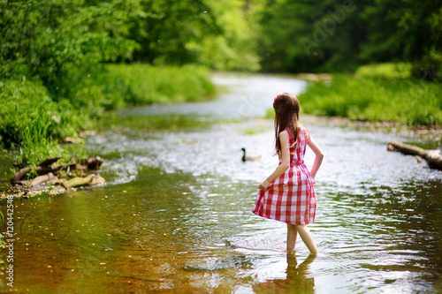 Cute little girl having fun by a river on sunny summer day
