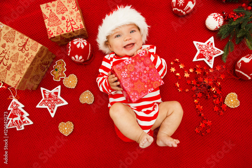 Baby first christmas. Beautiful little baby celebrates Christmas. New Year's holidays. Baby with santa hat with gift. Santa baby.
