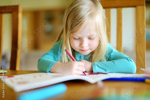 Cute little girl is drawing with colorful markers