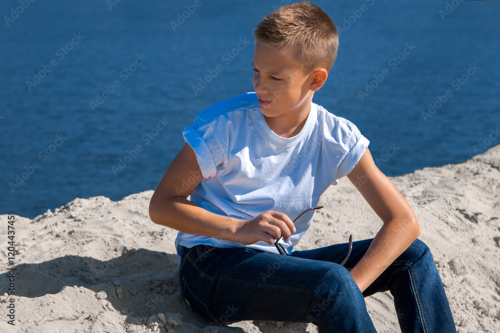 young stylish boy sits at the beach