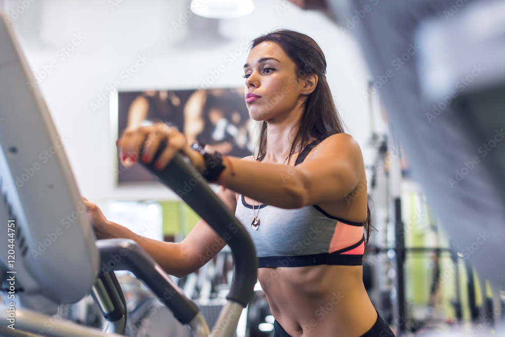 Fit woman doing cardio in an elliptical trainer in a gym. Fit woman doing cardio in an elliptical trainer in a gym.