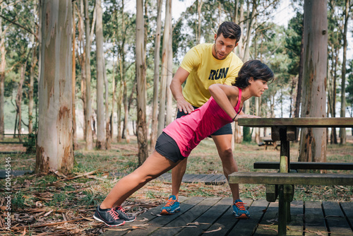 Tableau sur toile Sporty woman exercising with fitness trainer outdoor in forest