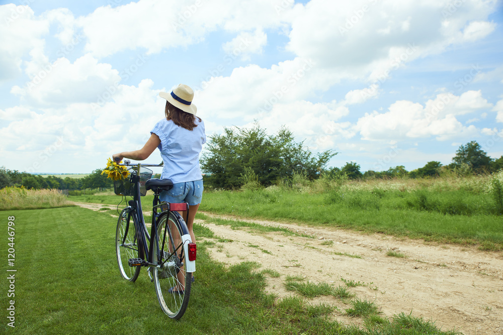 Relaxing outdoor. Young woman riding bike through a field. Rear view. Relaxing outdoor. Young woman riding bike through a field. Rear view.