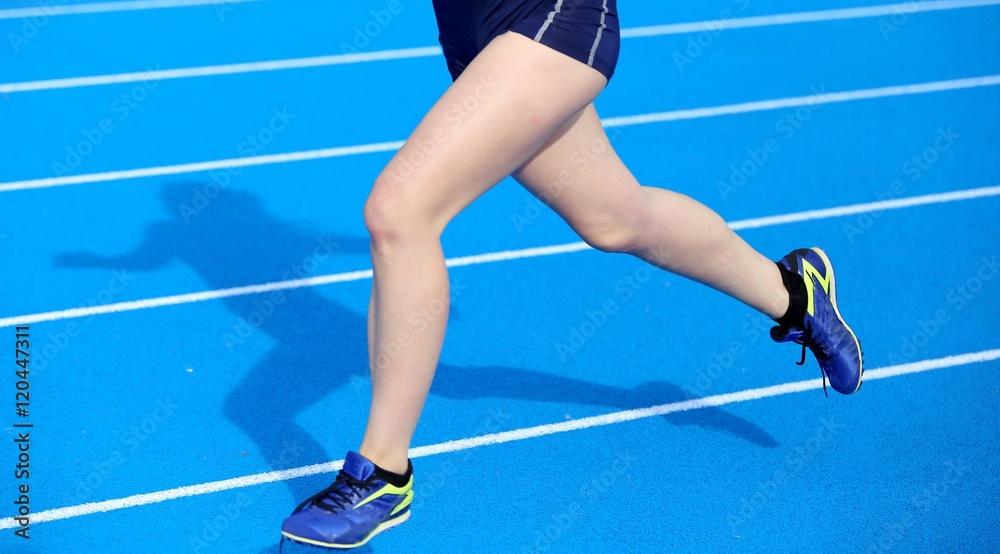 Fototapeta young woman running on the athletics track