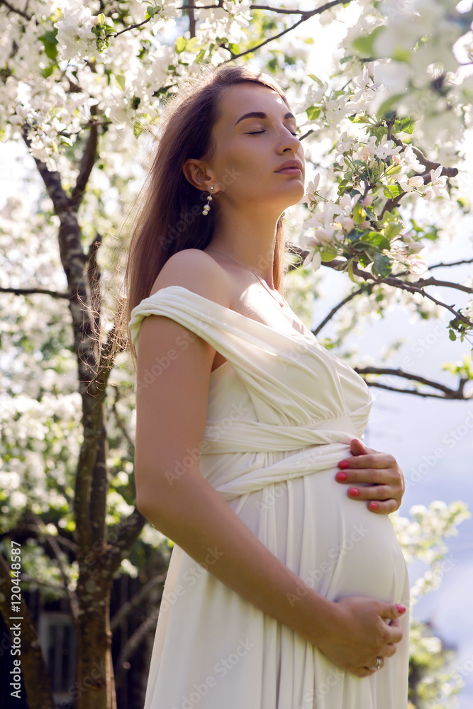pregnant girl with long hair wearing a white dress standing pregnant girl with long hair wearing a white dress standing