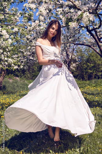 pregnant girl with long hair wearing a white dress standing