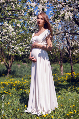 pregnant girl with long hair wearing a white dress standing