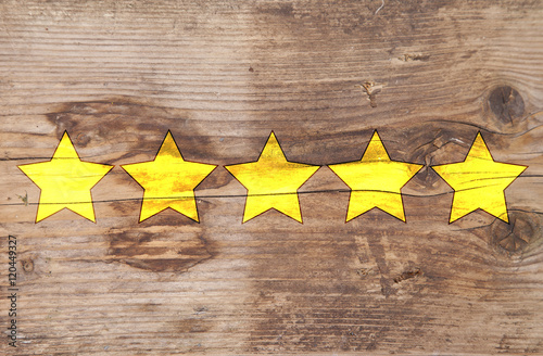 Five yellow ranking stars on wooden background