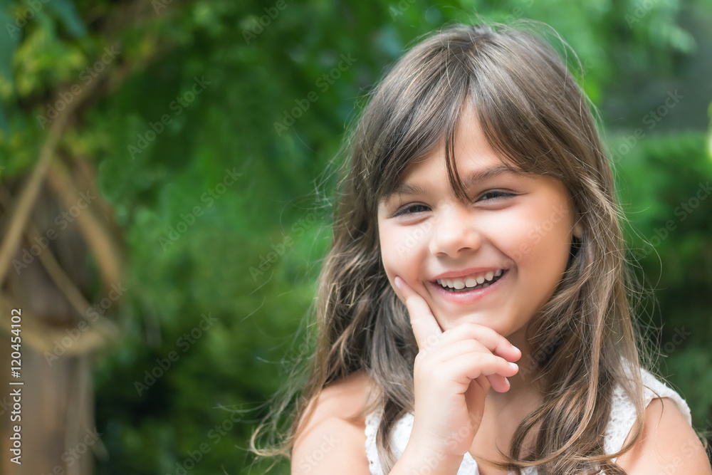 Portrait of laughing attractive little girl looking at the camera. Girl's hand supporting cheek. Portrait of laughing attractive little girl looking at the camera. Girl's hand supporting cheek.